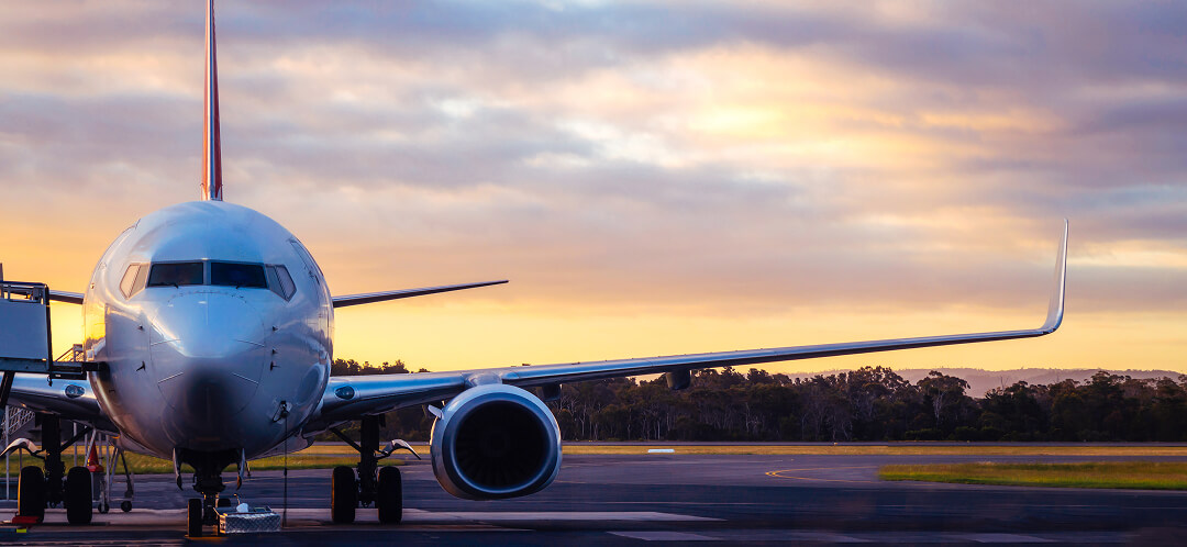 commercial airplane on airport runway at sunset