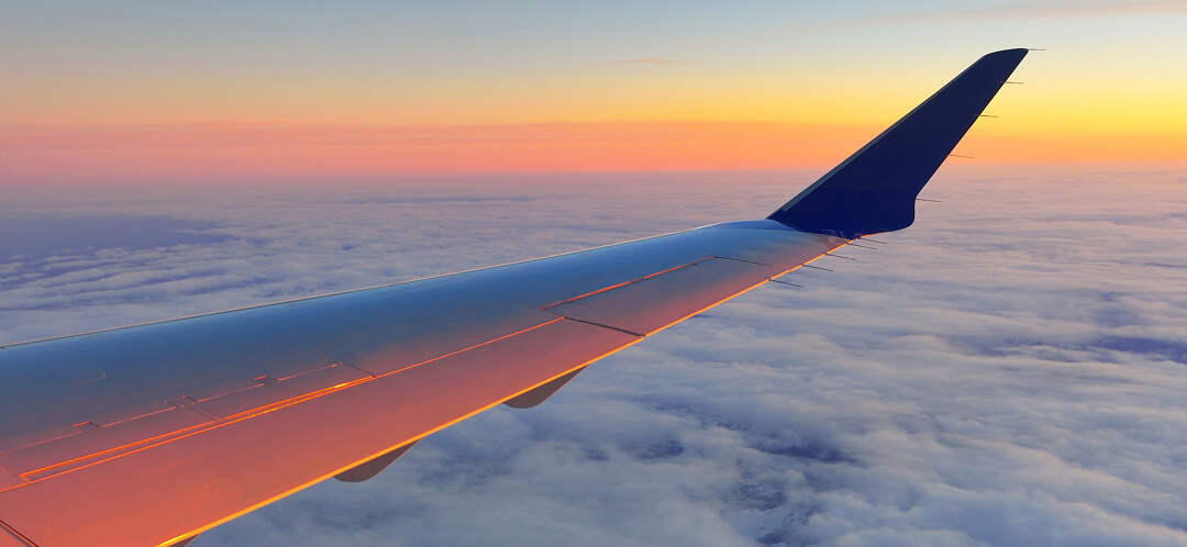 airplane wing above clouds at sunset