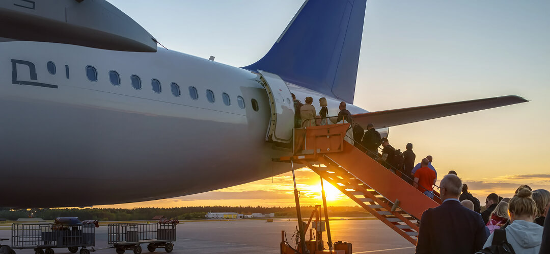 passengers boarding airplane at sunset